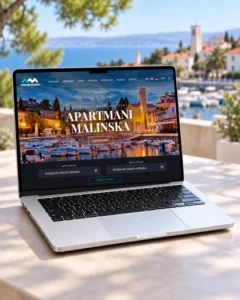 Web stranica Apartmani Malinska prikazana na laptopu s obalom i barkama u pozadini.