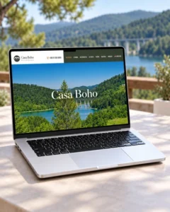Web stranica kuće za odmor Casa Boho prikazana na laptopu s jezerom i šumom u pozadini.