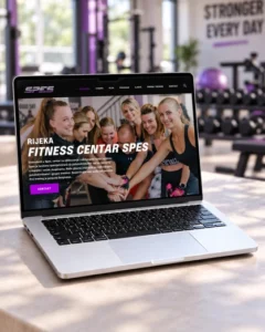 Web stranica Fitness centra SPES Rijeka prikazana na laptopu s teretanom u pozadini.